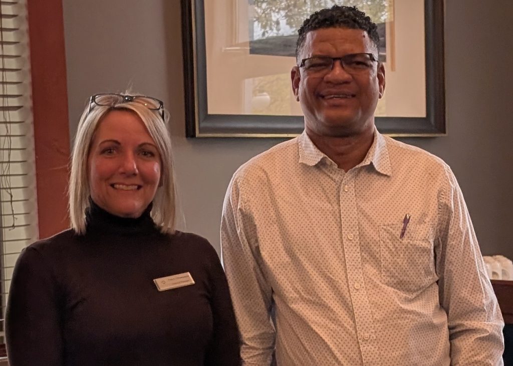 Two people standing together in a restaurant posing for a picture. Nancy Champagne talking with Vilfort Metellus about working on the Hotel Industry.